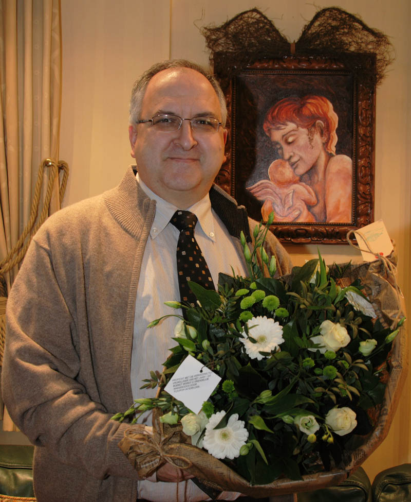 Foto van Marc Van Gestel met in de achtergrond het schilderij Kapotte Engel van Belinda Meuldijk